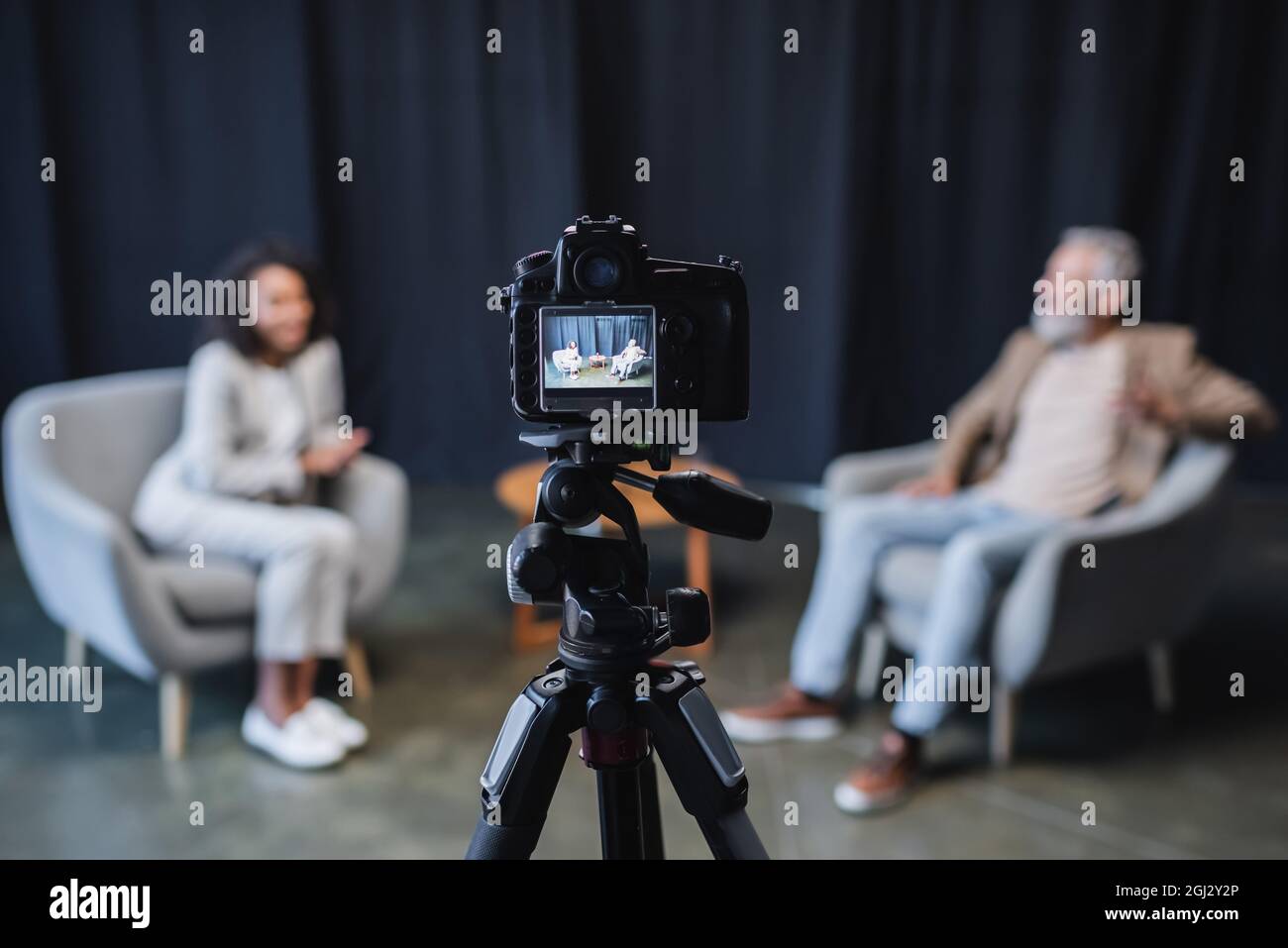 digital camera with businessman in suit sitting in grey armchair during