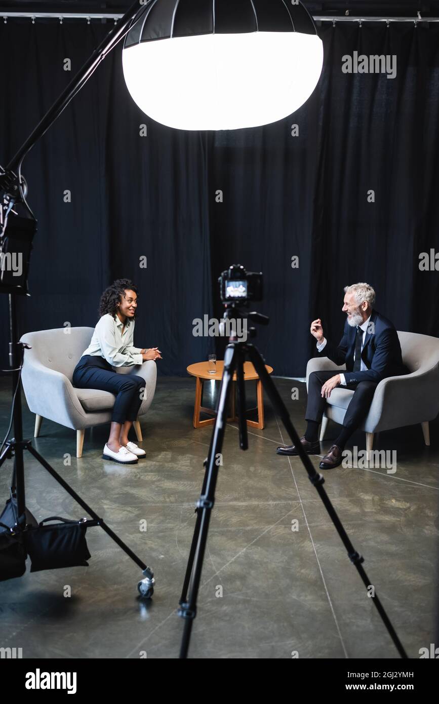 happy african american journalist sitting in armchair and talking with