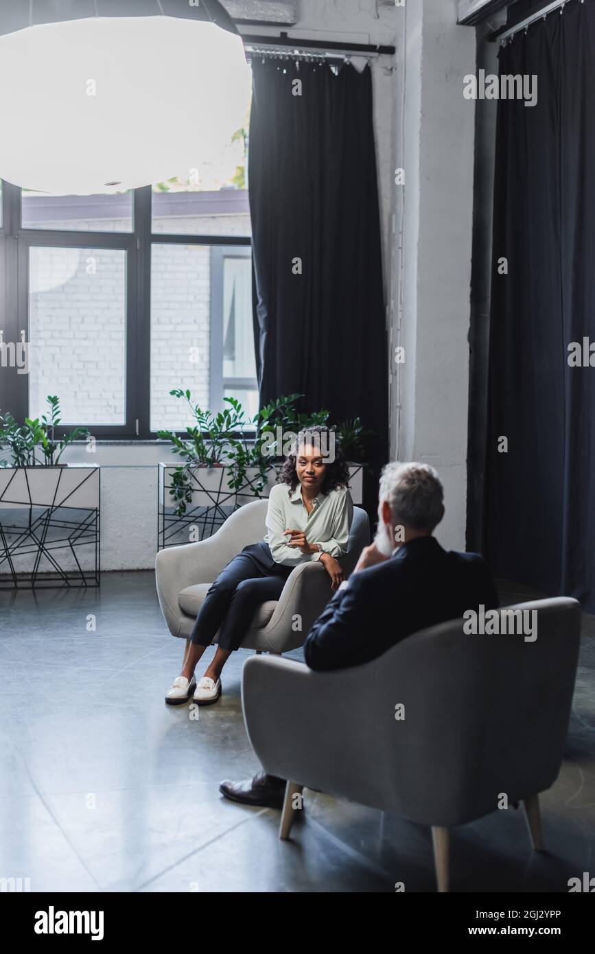 african american journalist sitting in armchair and talking