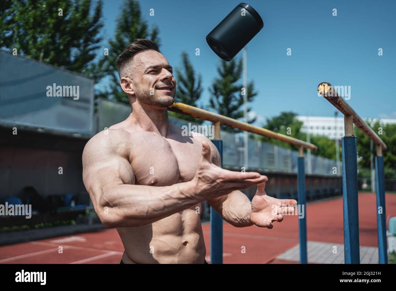 muscular athlete man throw up black container with protein whey powder outdoor Stock Photo