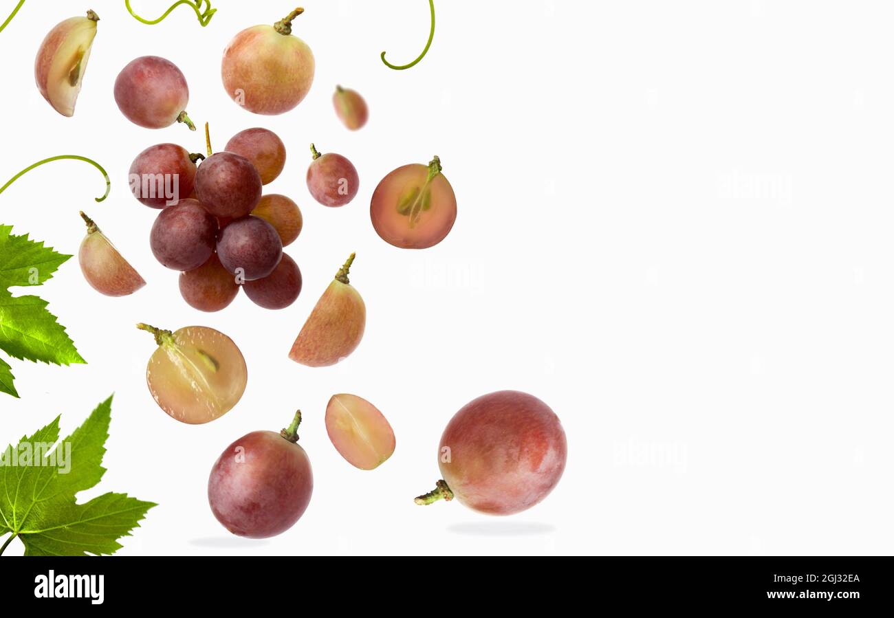 Falling red grape with leaves, isolated on white background, selective focus Stock Photo