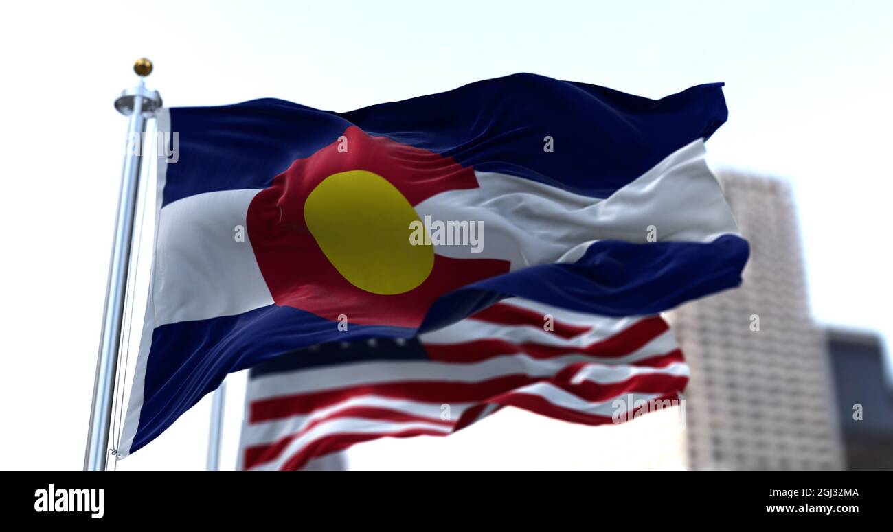 the flag of the US state of Colorado waving in the wind with the American stars and stripes flag blurred in the background. Colorado was it admitted i Stock Photo