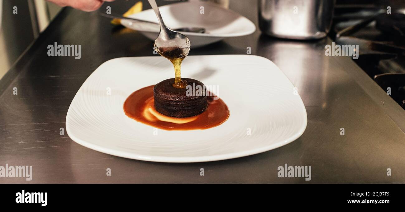 Chef putting the finishing touch on dessert plate while working in a restaurant kitchen. Stock Photo