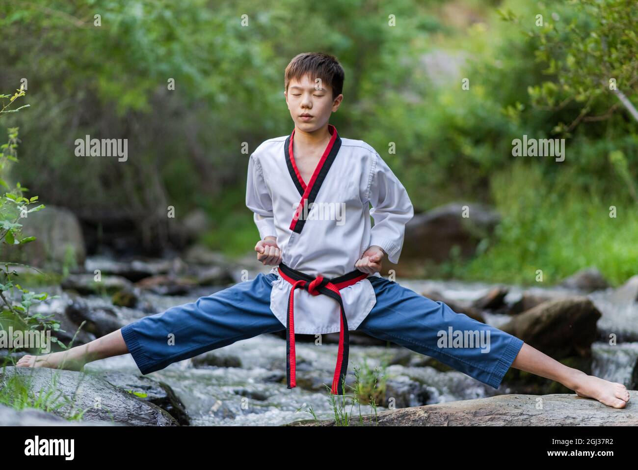 Boy performing martial arts while doing a standing pose on rocks in a