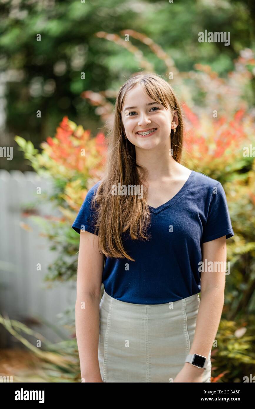 A teenage girl with long brown hair standing outside in a navy shirt Stock Photo