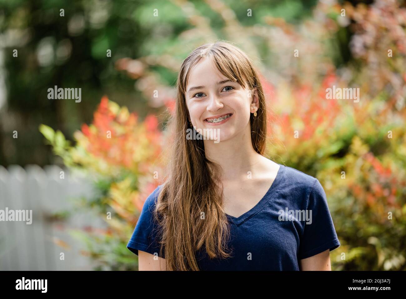 A teenage girl with long brown hair standing outside in a navy shirt Stock Photo