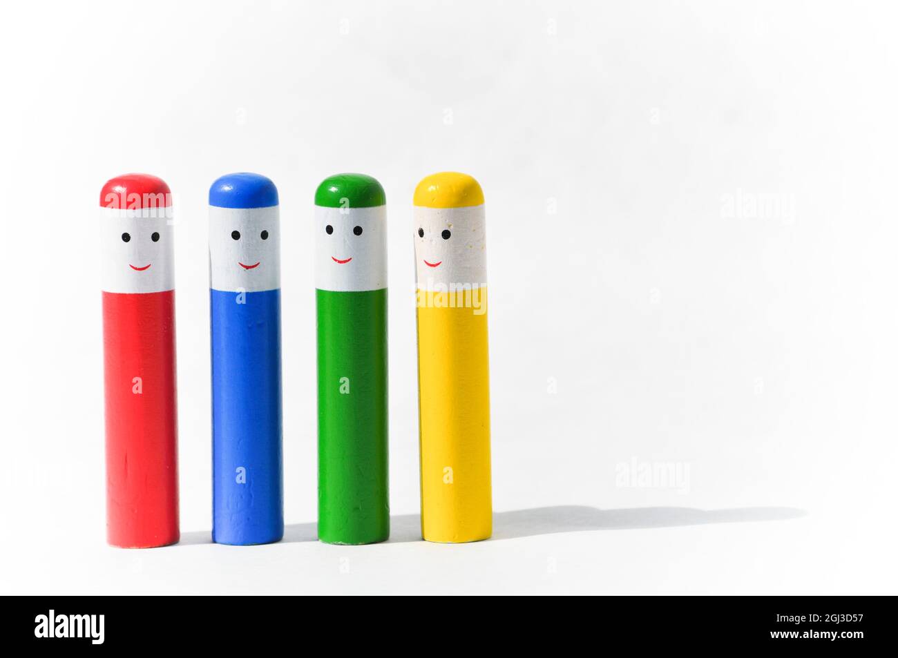 Wooden toddler pop up toy. A wooden toy set against a white background. Four multicoloured wooden peg people with happy faces Stock Photo