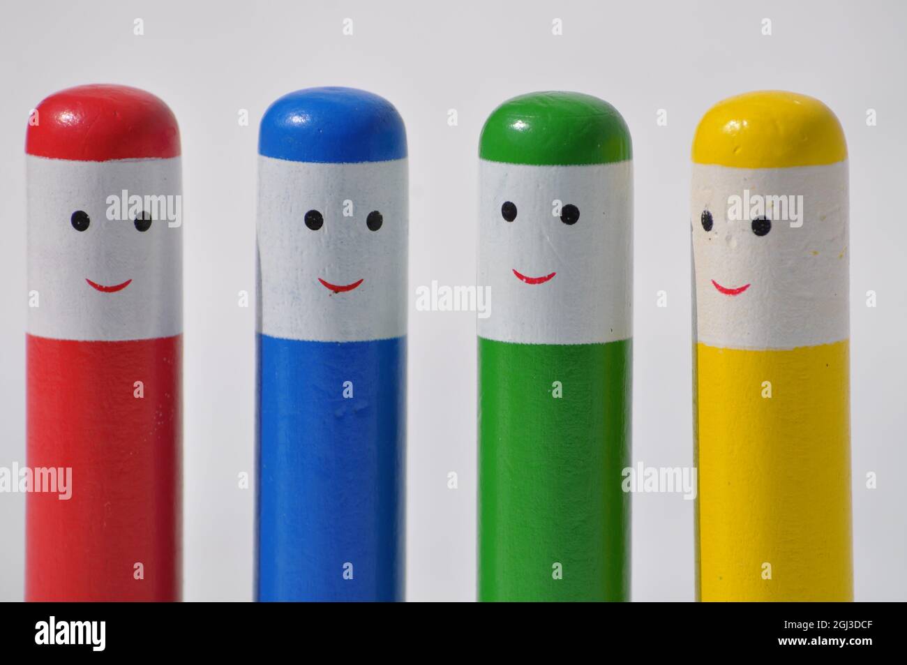 Wooden toddler pop up toy. Four multicoloured wooden peg people with happy faces set against a white background Stock Photo