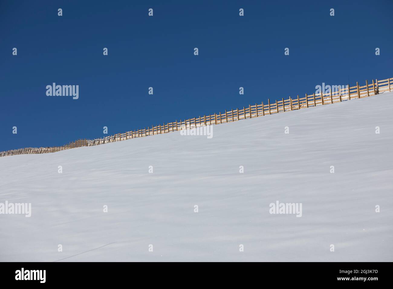 Snow covered field with fence in a blue sky, caption space, bluebird powder day Stock Photo