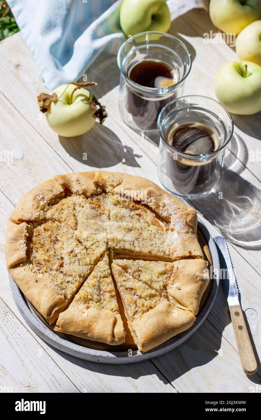 Apple galette with hazelnut streusel, served with coffee on a wooden background. Rustic style. Stock Photo