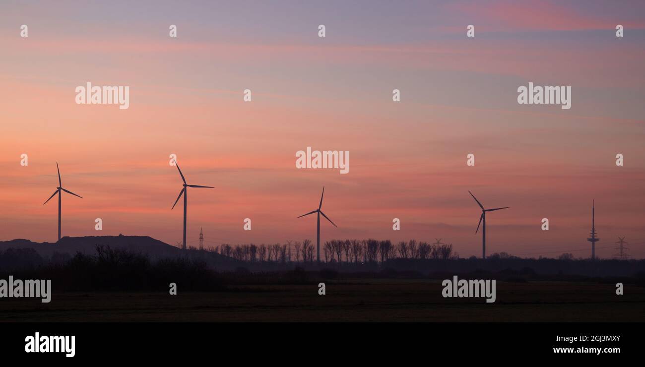 panorama shot of wind turbines at sunrise with beautiful, colorful sky in the background Stock Photo