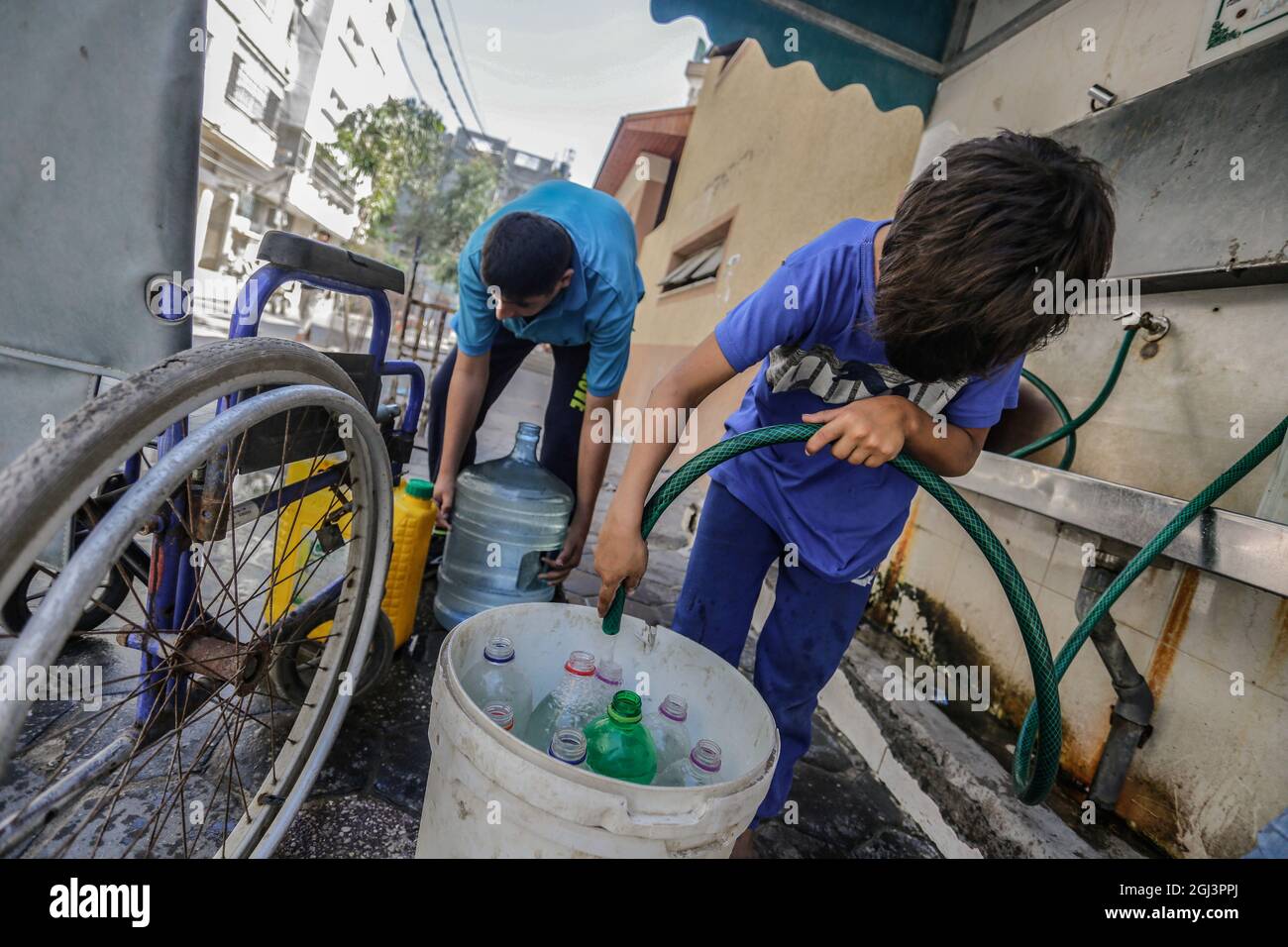 Palestinian children fill plastic bottles and jerrycans with drinking