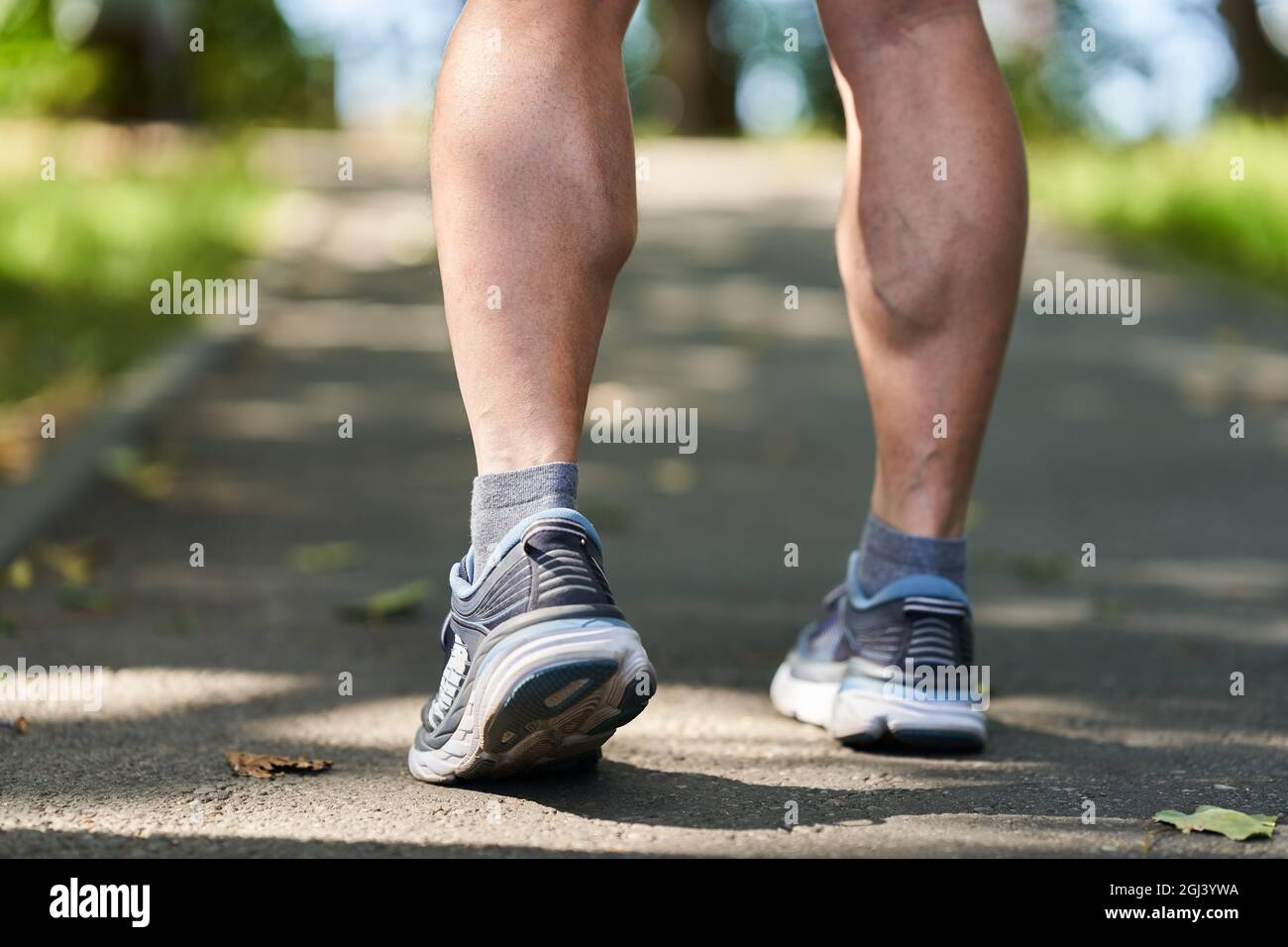 Closeup on the muscular calves and shoes of a marathon runner on an