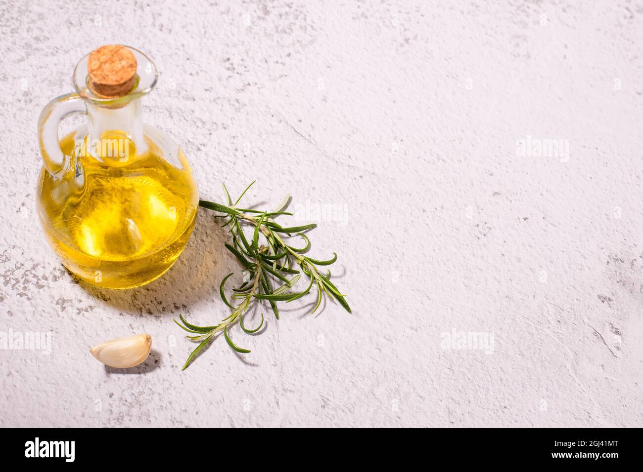 Cooking ingredients: Aa glass jar with virgin olive oil, olive branch, garlic clove and rosemary Stock Photo