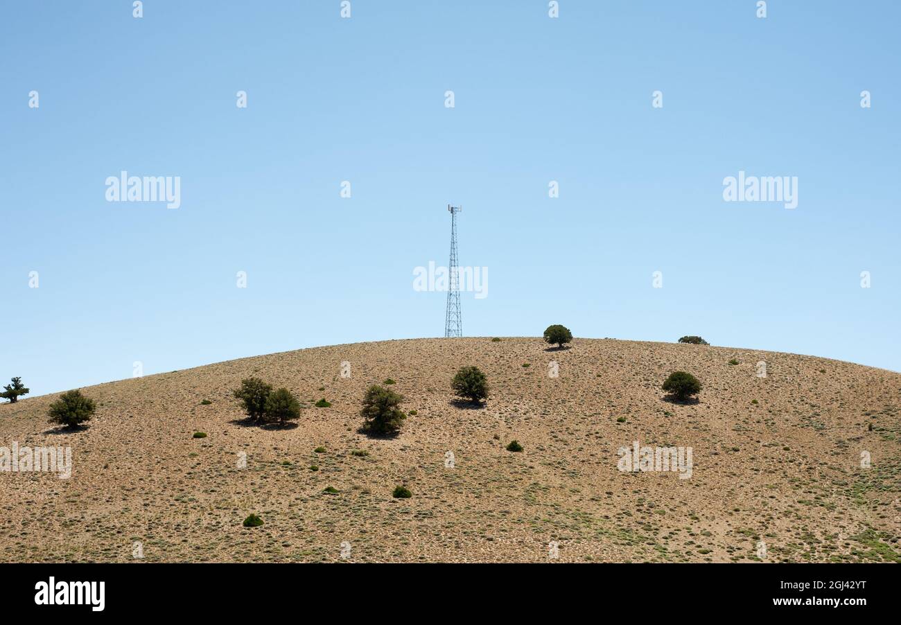 rounded hill with some trees, Radio tower and blue sky in mazandaran province, Iran Stock Photo