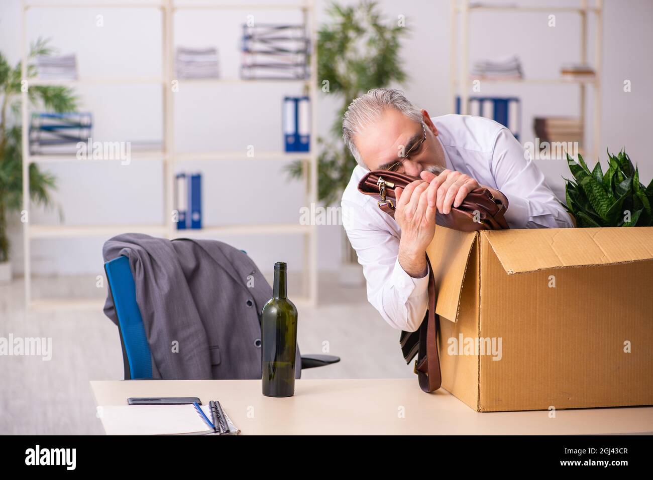 Old alcohol addicted employee in dismissal concept Stock Photo - Alamy