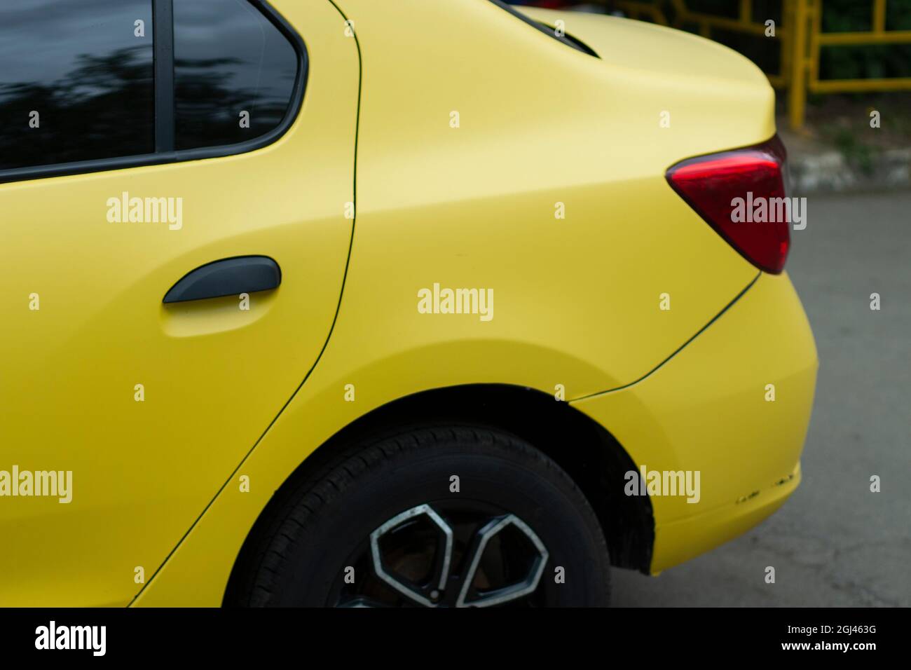 The back of the yellow car. Trunk and rear wheel in the vehicle. Door