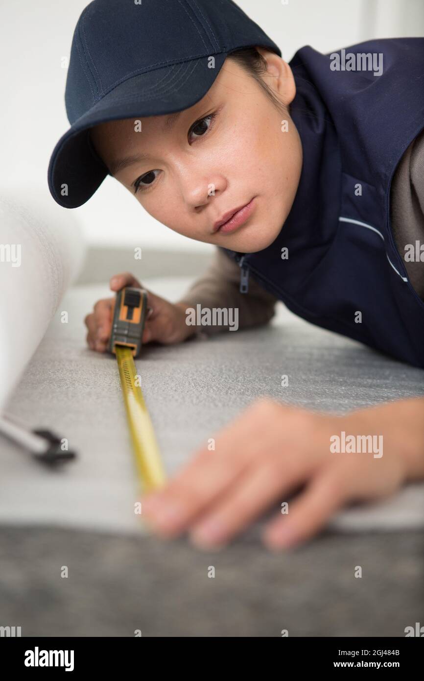 female repairman measuring carpet Stock Photo