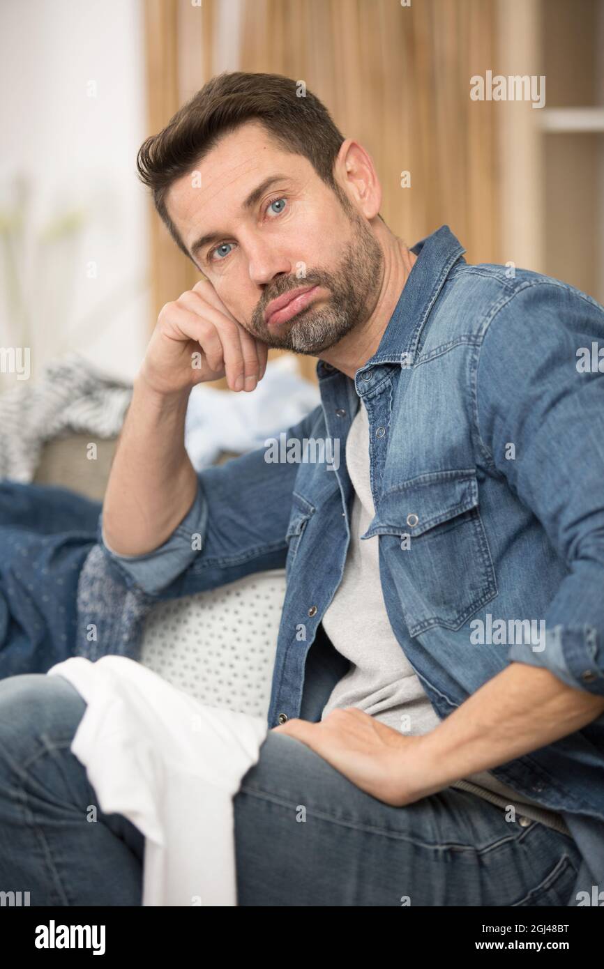 unmotivated man sighing as he does the laundry Stock Photo