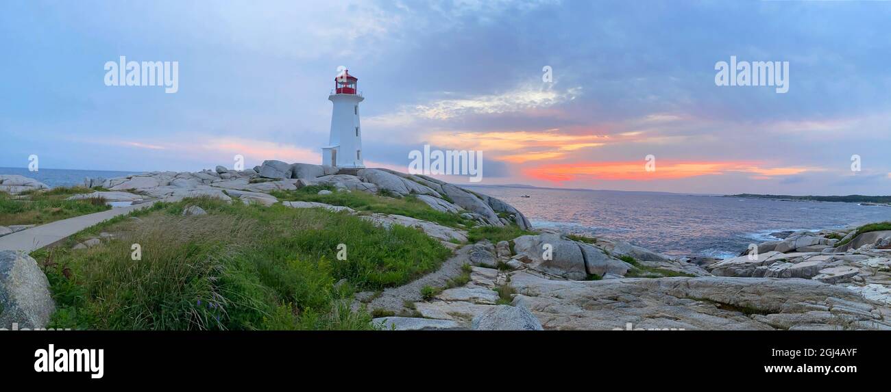 Peggy’s Cove Lighthouse illuminated at sunset with dramatic skyon the foreground, Nova Scotia, Canada Stock Photo