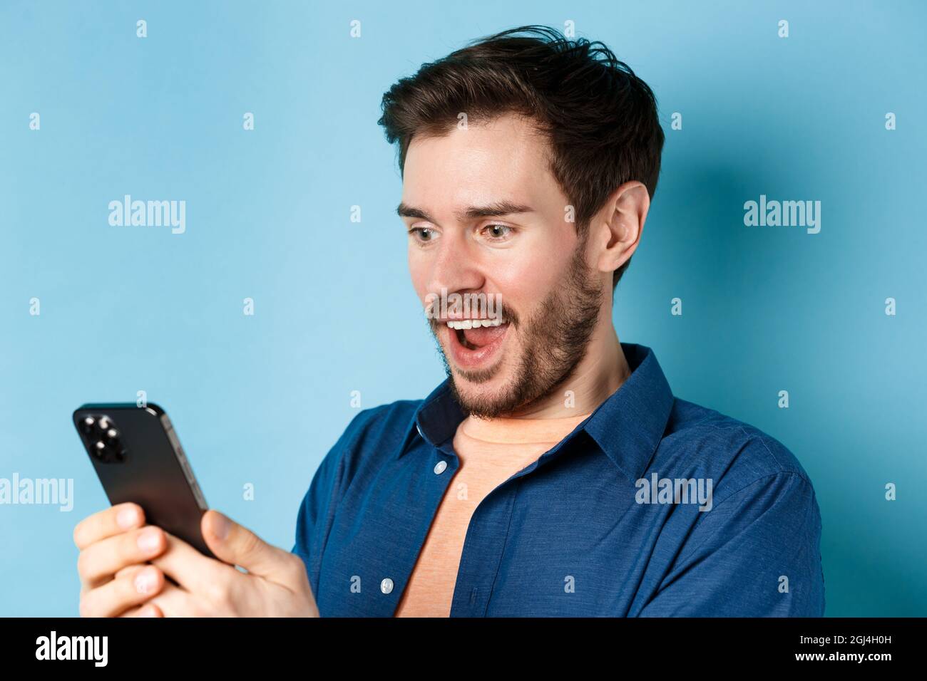 Image of handsome young man feeling happy reading good news on mobile ...