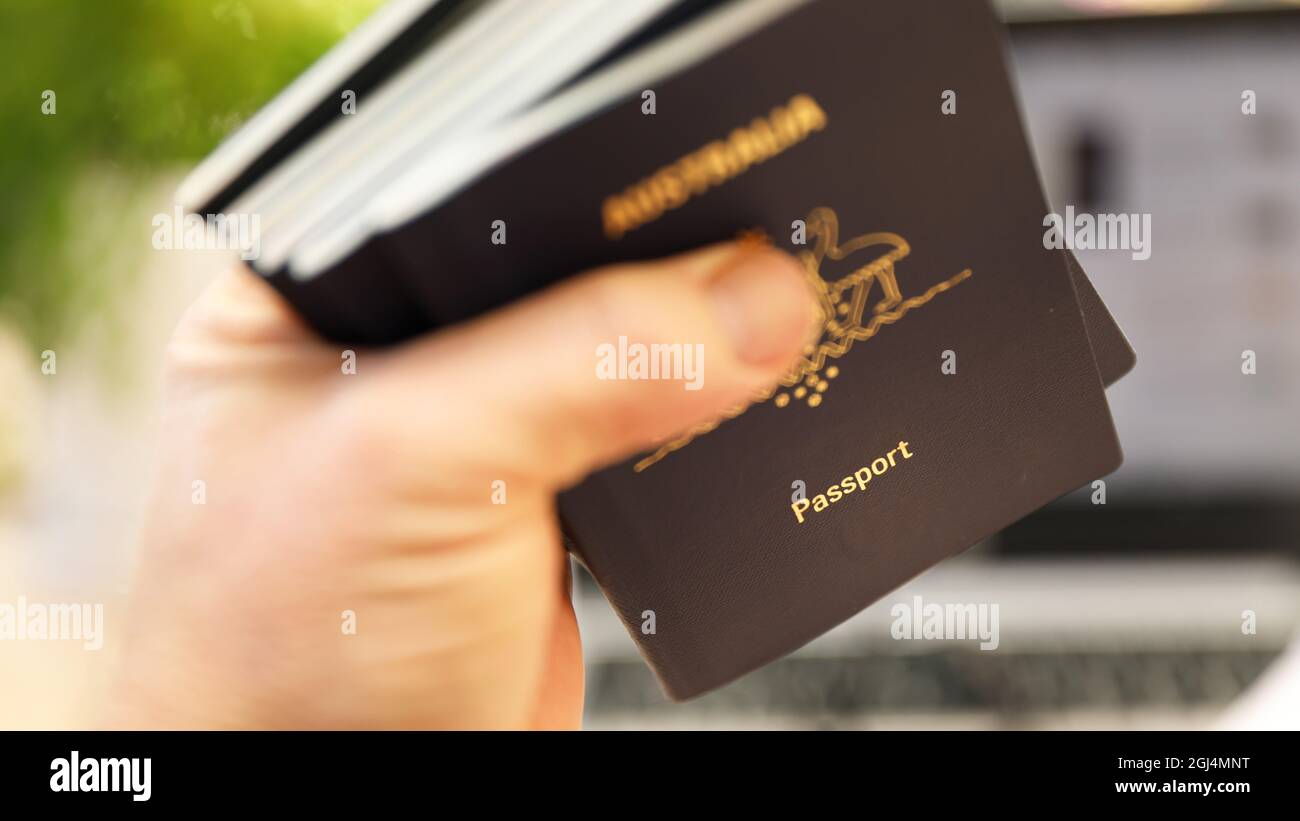 An out of focus hand holding a large number (5) passports. Shallow depth of field, deliberately blurred to reveal only the word passport. Stock Photo