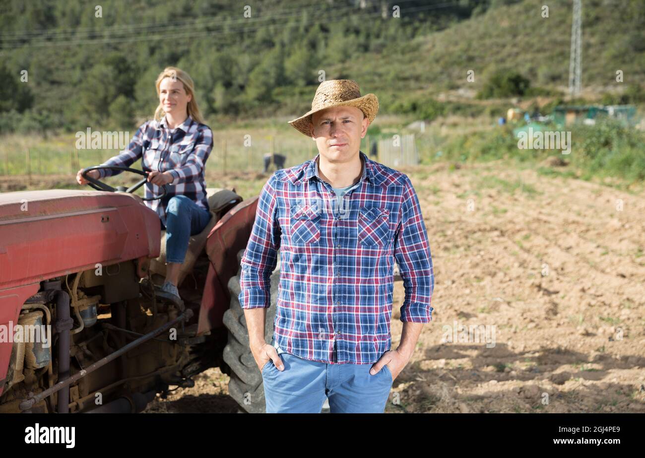 Farmer on background with wife on tractor Stock Photo - Alamy