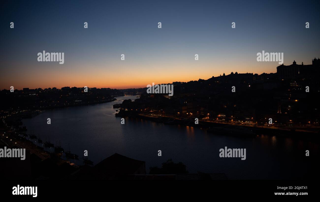 Low Sunset with Gradient - Orange Green Yellow Blue - City in View alongside River in Porto Portugal Stock Photo