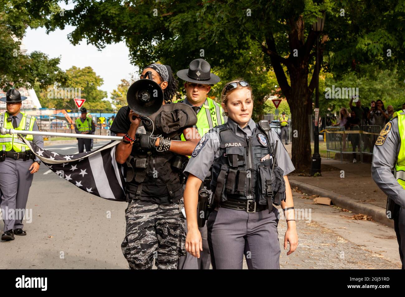 Richmond, VA, USA, 8 September, 2021.  Pictured: Richmond Police Officer Pajda and Virginia state troopers escort Japhari Jones of Richmond out of the barricaded area as the statue of Confederate general Robert E. Lee is removed from its enormous pedestal on Monument Avenue.  The Virginia supreme court ruled last week that the six-story monument could be removed.  It has yet to be determined whether the pedestal covered in anti-racism graffiti will be removed given its prominent role in the 2020 anti-racism uprising in Richmond.  Credit: Allison Bailey / Alamy Live News Stock Photo