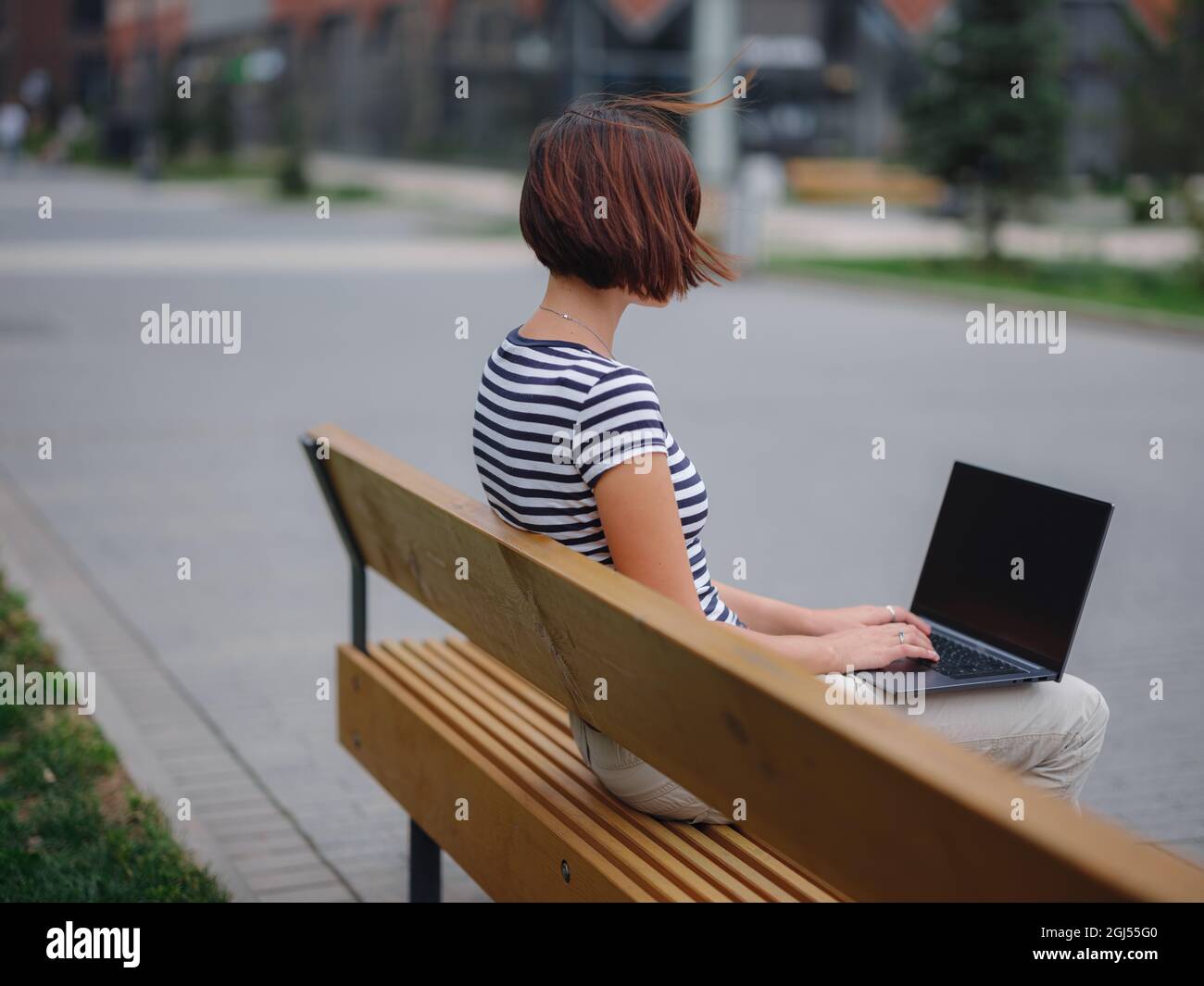 Young asian female student working at laptop sit down on bench outside ...