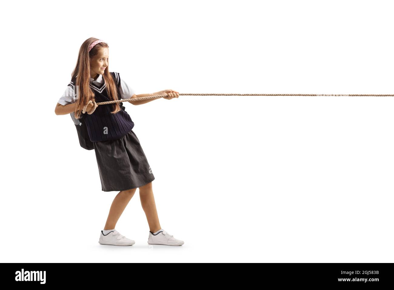 Full length profile shot of a schoolgirl pulling a rope isolated on white background Stock Photo