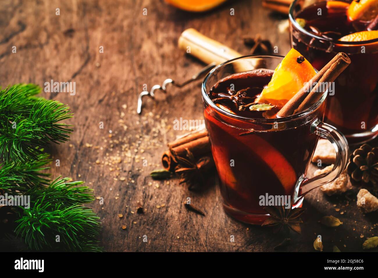 Winter hot mulled red wine in glass cup on wooden rustic table. Traditional Christmas or New Year drink in festive table setting Stock Photo