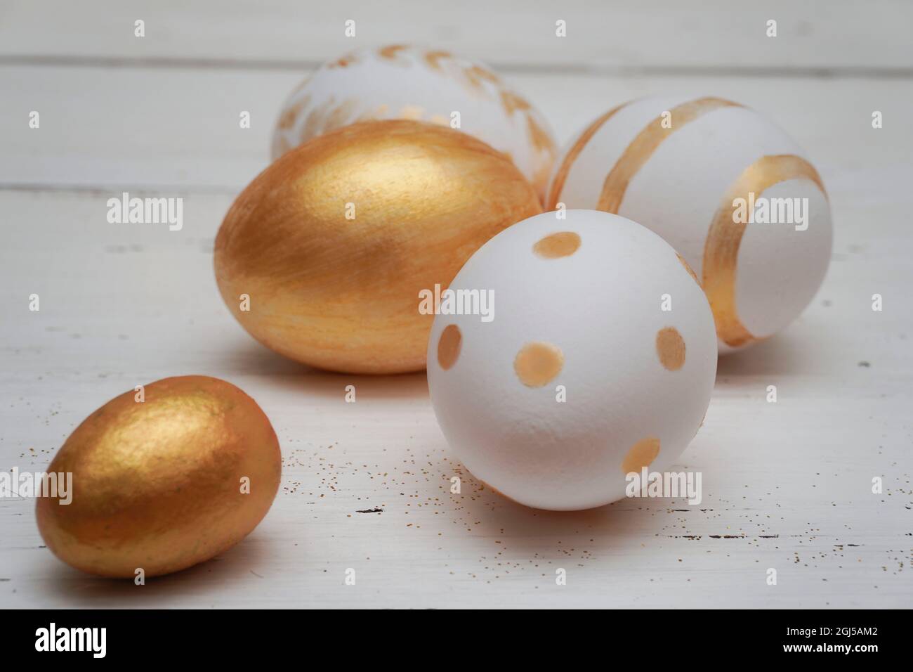 Golden Easter eggs on rustic old wooden background. Trendy Easter composition. Copy space for text. Minimal Easter concept. Stock Photo