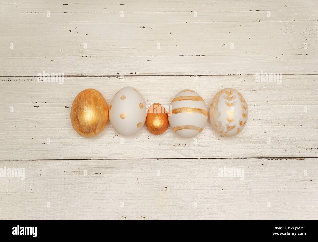 Golden Easter eggs on rustic old wooden background. Trendy Easter flat lay composition. Copy space for text. Minimal Easter concept. Happy Easter day Stock Photo
