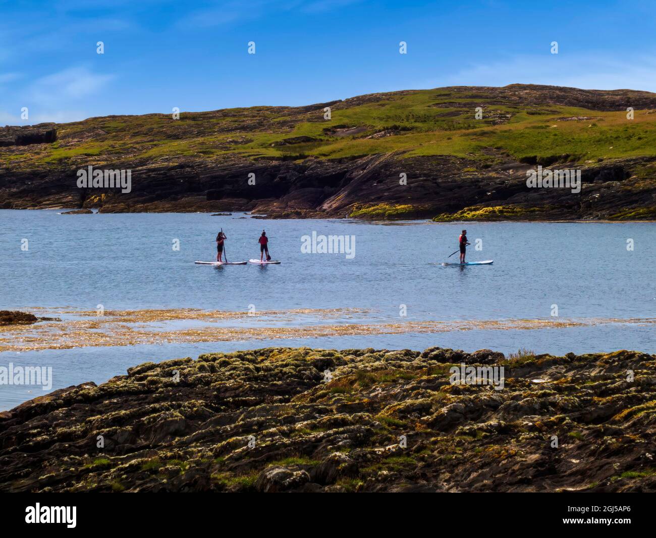 People on paddling boards in a calm cove of Irish Atlantic shoreline.County Cork, Ireland. Stock Photo