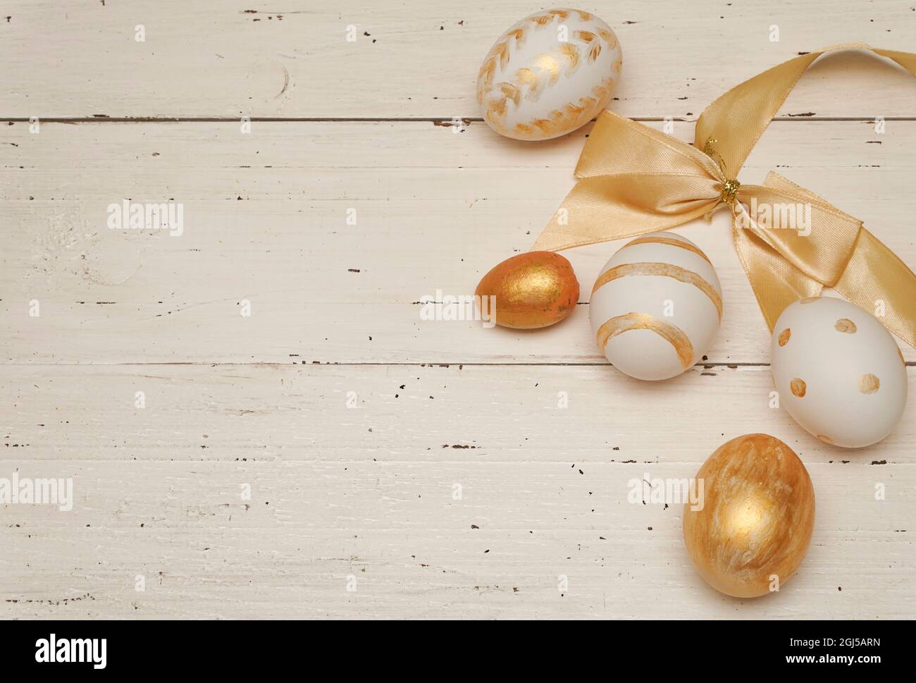 Golden Easter eggs on white rustic old wooden background. Trendy Easter flat lay composition. Copy space for text. Minimal Easter concept. Easter deco Stock Photo