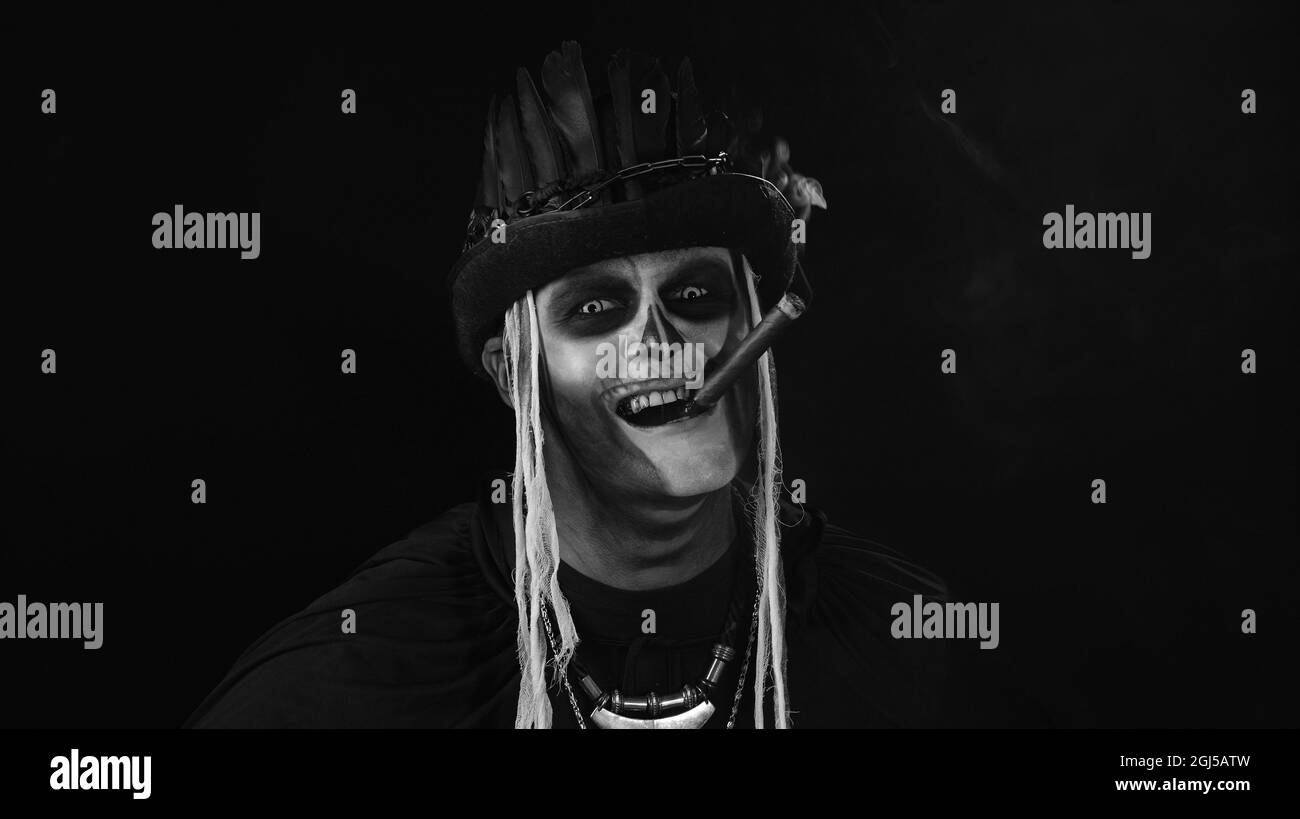 Frightening man in skeleton Halloween cosplay costume smoking cigar, smiling, laughing Stock Photo