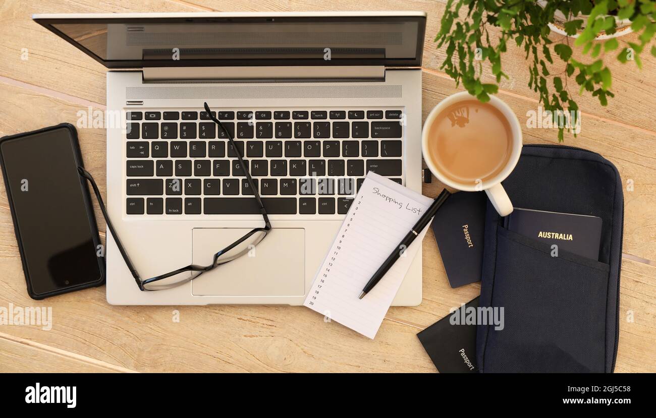 A lay flat arrangement view from above of travel documents. Australian passport, phone, cup of tea and computer laptop ready to start booking internat Stock Photo