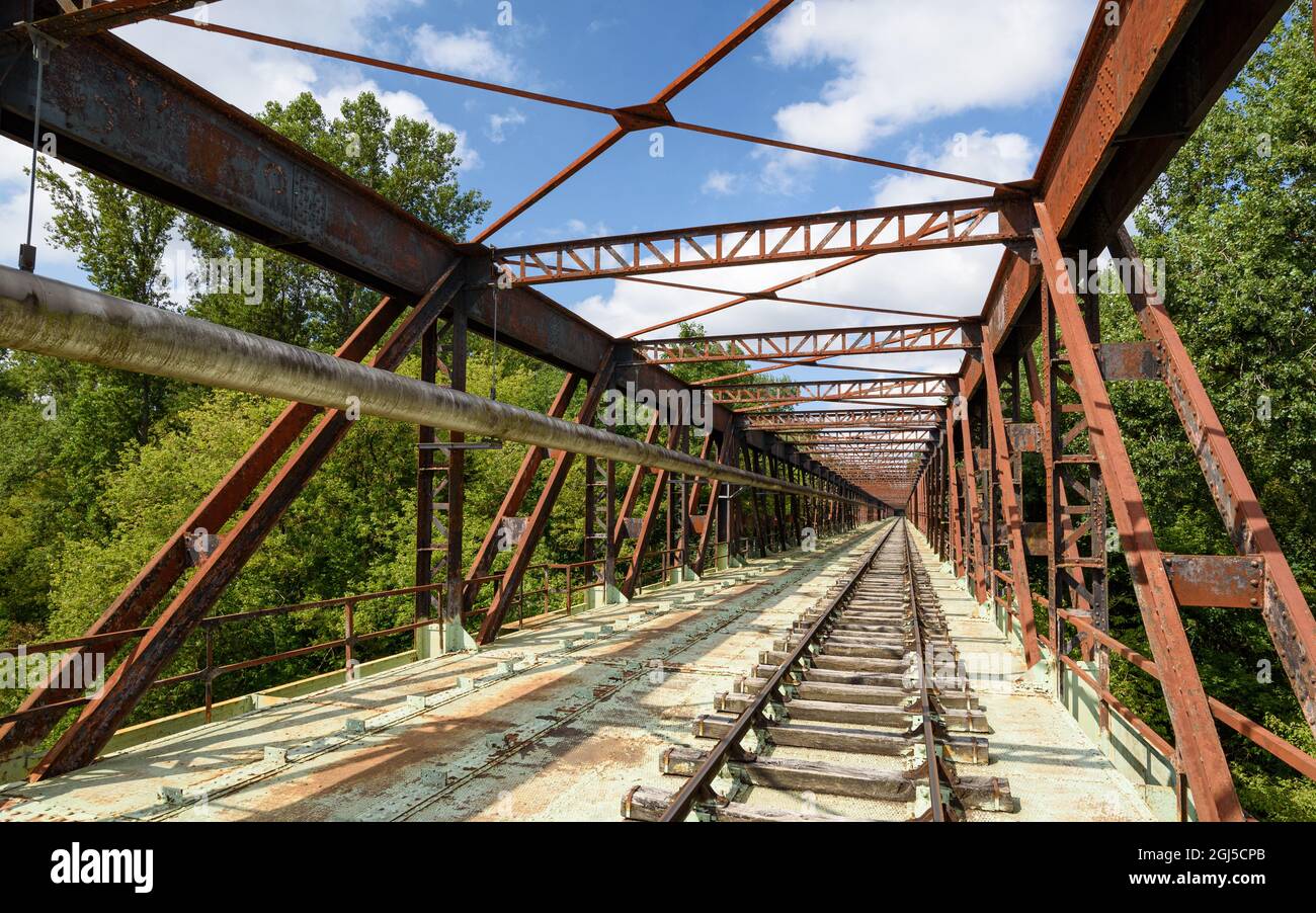 Old railway line crossing a rusty bridge turned into recreational track for rail-cycle draisine with four wheels. Stock Photo
