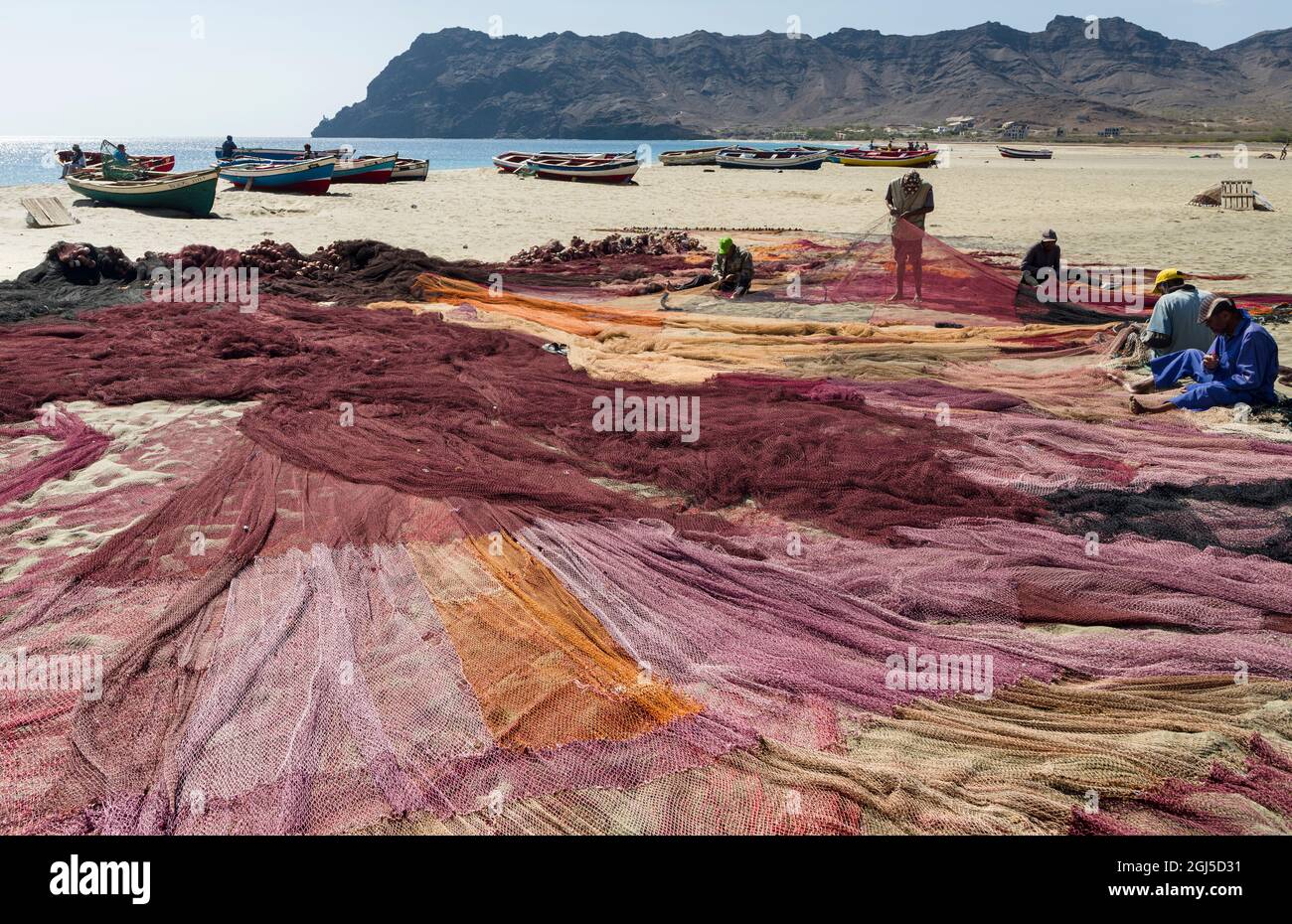 Fishermen are mending their colorful fishing nets on a beach near Sao ...