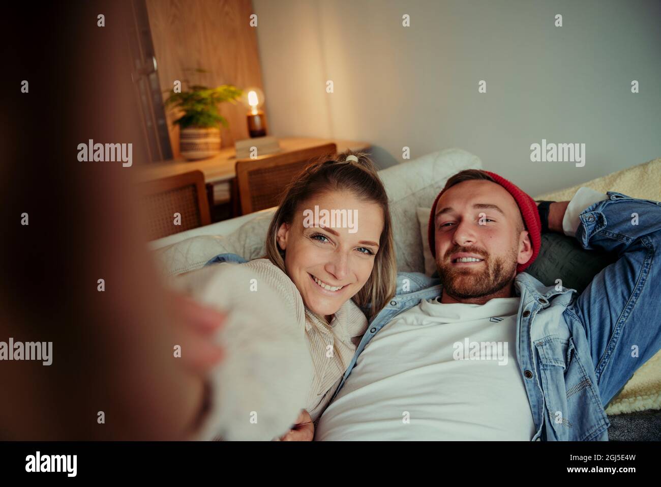 Happy caucasian couple sitting on sofa taking selife Stock Photo