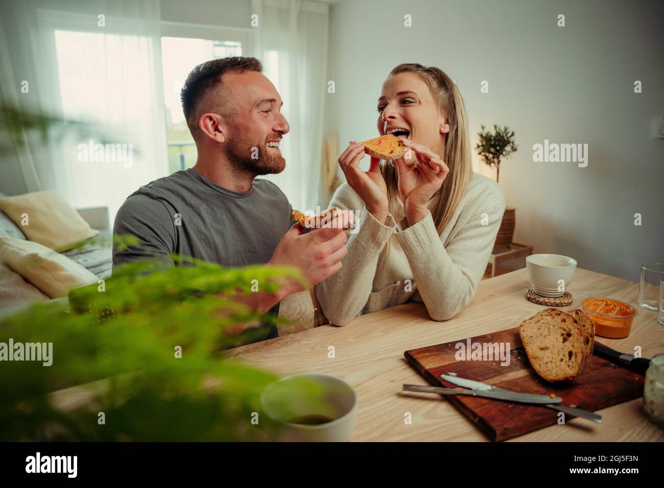 Romantic caucasian couple sitting in kitchen eating breakfast  Stock Photo