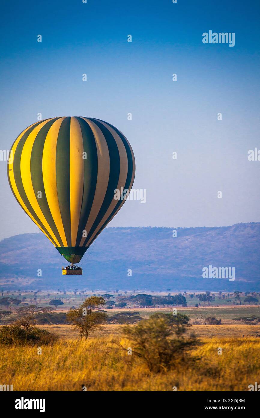 A hot-air balloon slowly traverses over the Serengeti plain. Stock Photo
