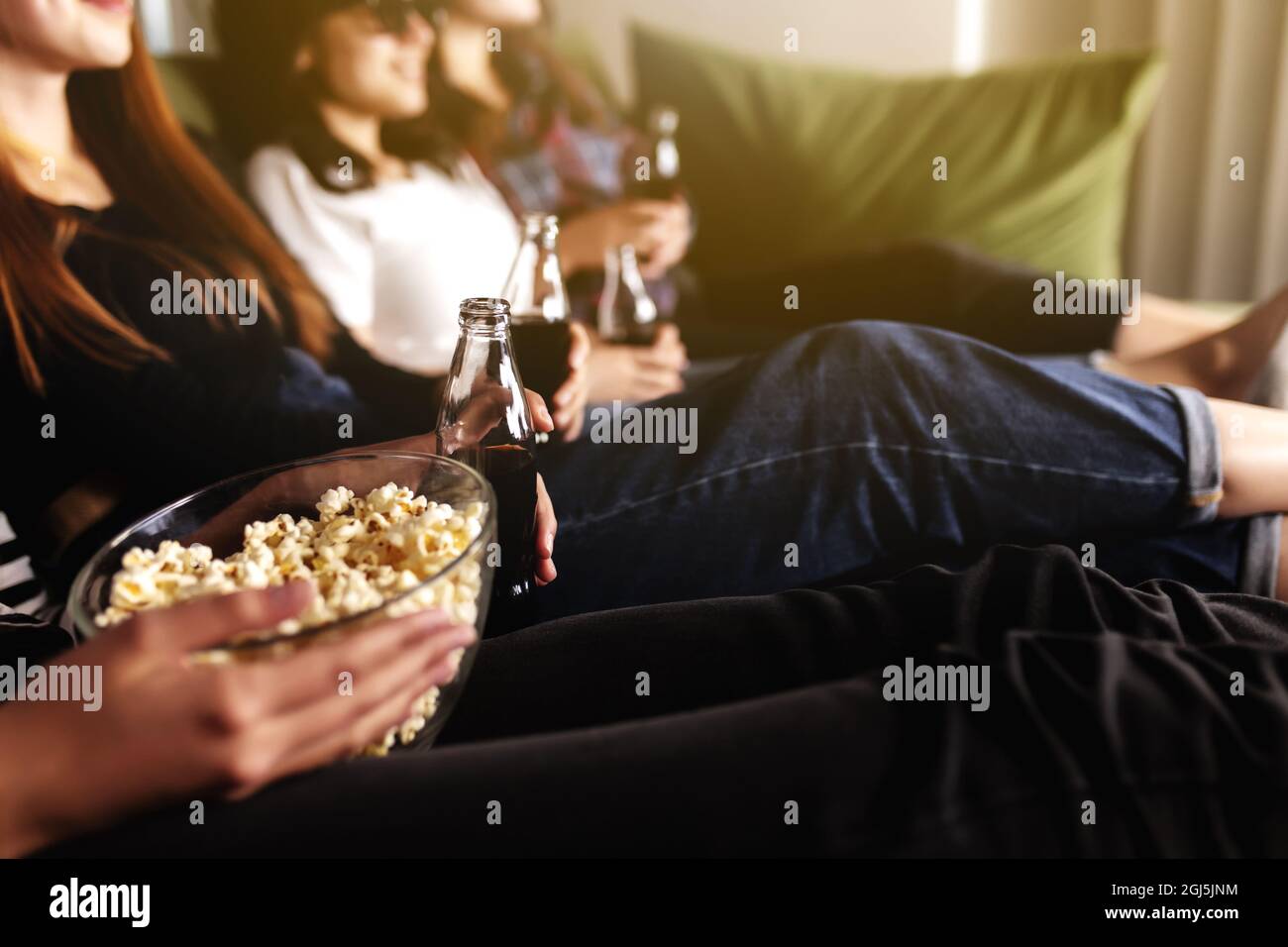 Friend group of people in 3D glasses are watching a movie, smiling, laughing. Eating and drinking while watching a movie in the cinema. Girls eat popc Stock Photo
