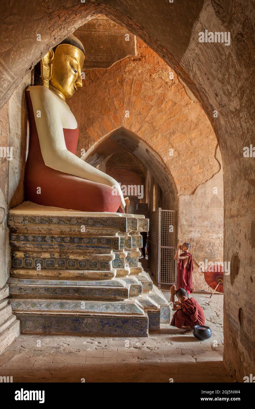 Myanmar, Bagan. Novice Buddhist monks at Buddha statue. Stock Photo