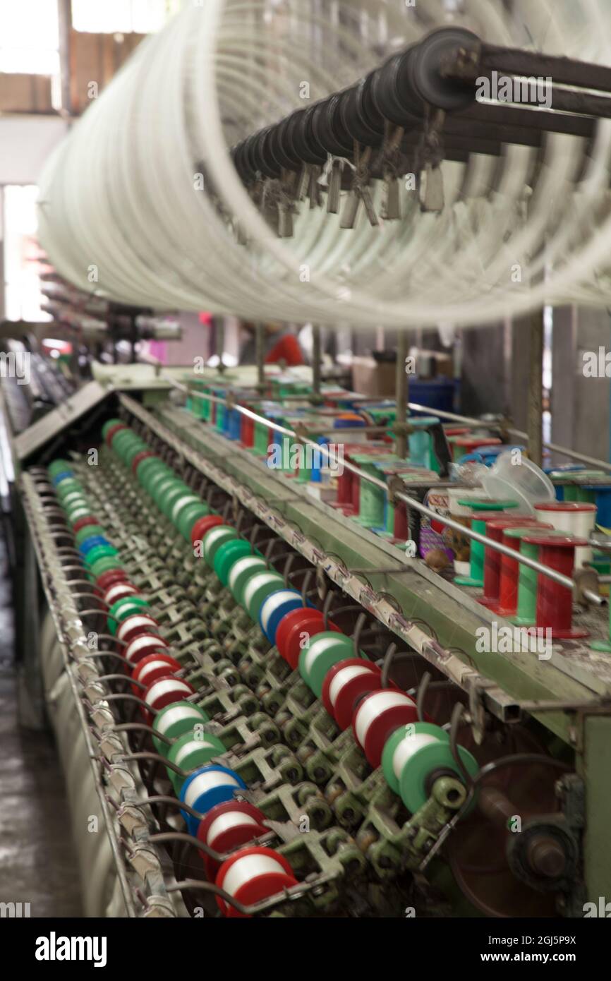 Industrial machines making cotton threads on spools in fabric factory