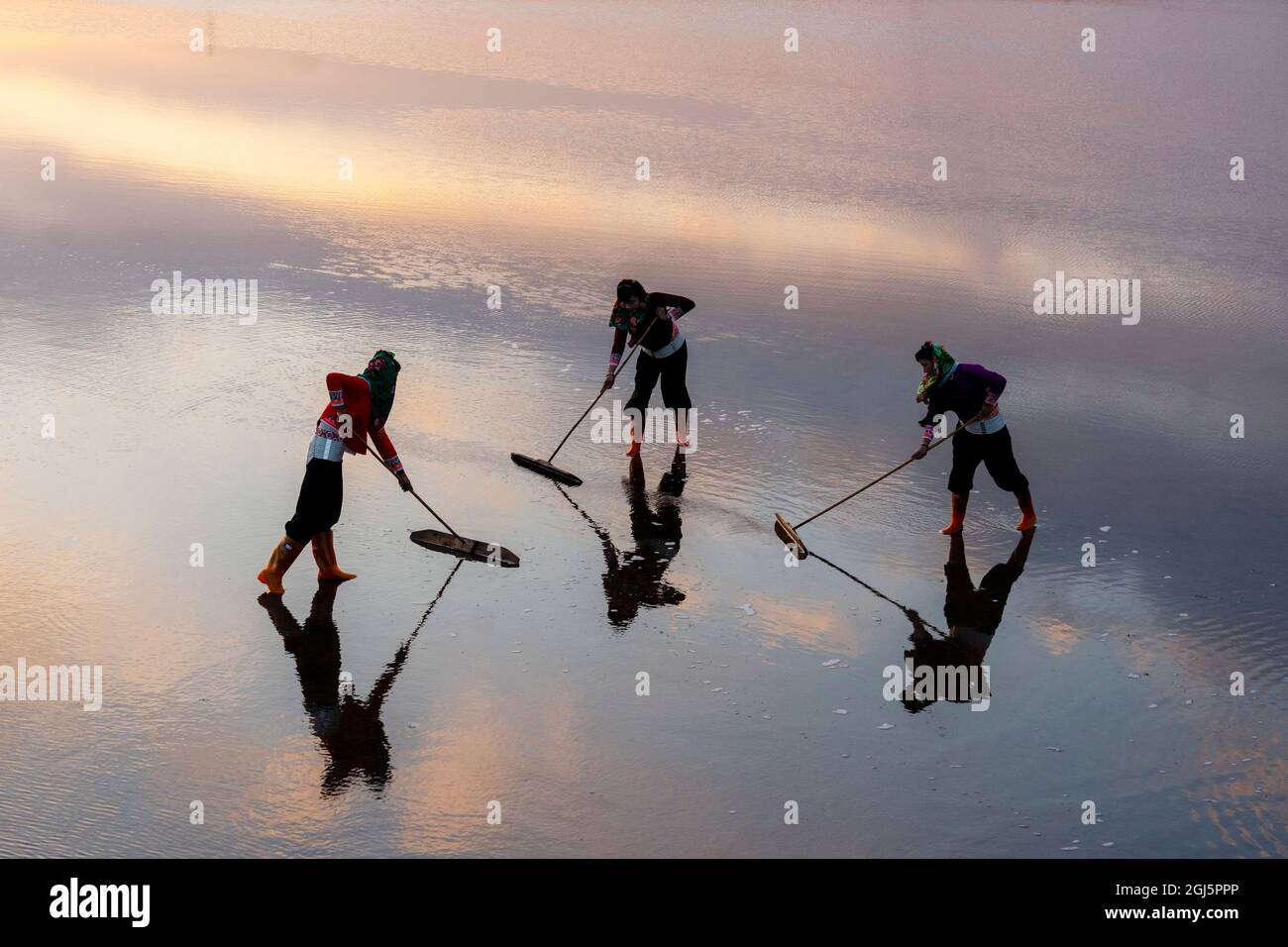 China, Fujian Province, Hui'an. Girls sweep the salt flats to keep the