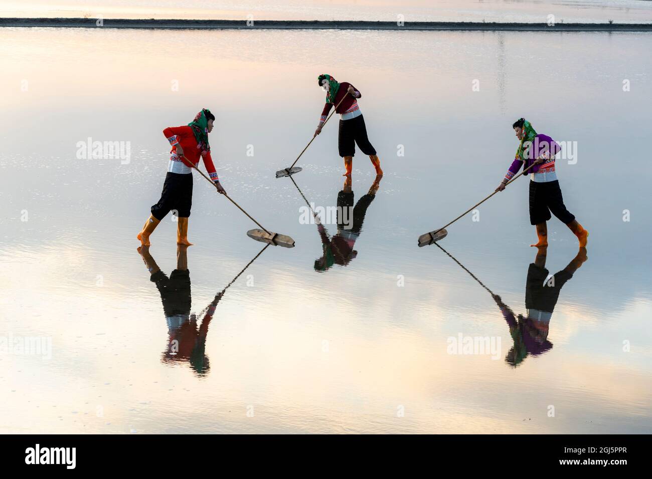 China, Fujian Province, Hui'an. Girls sweep the salt flats to keep the