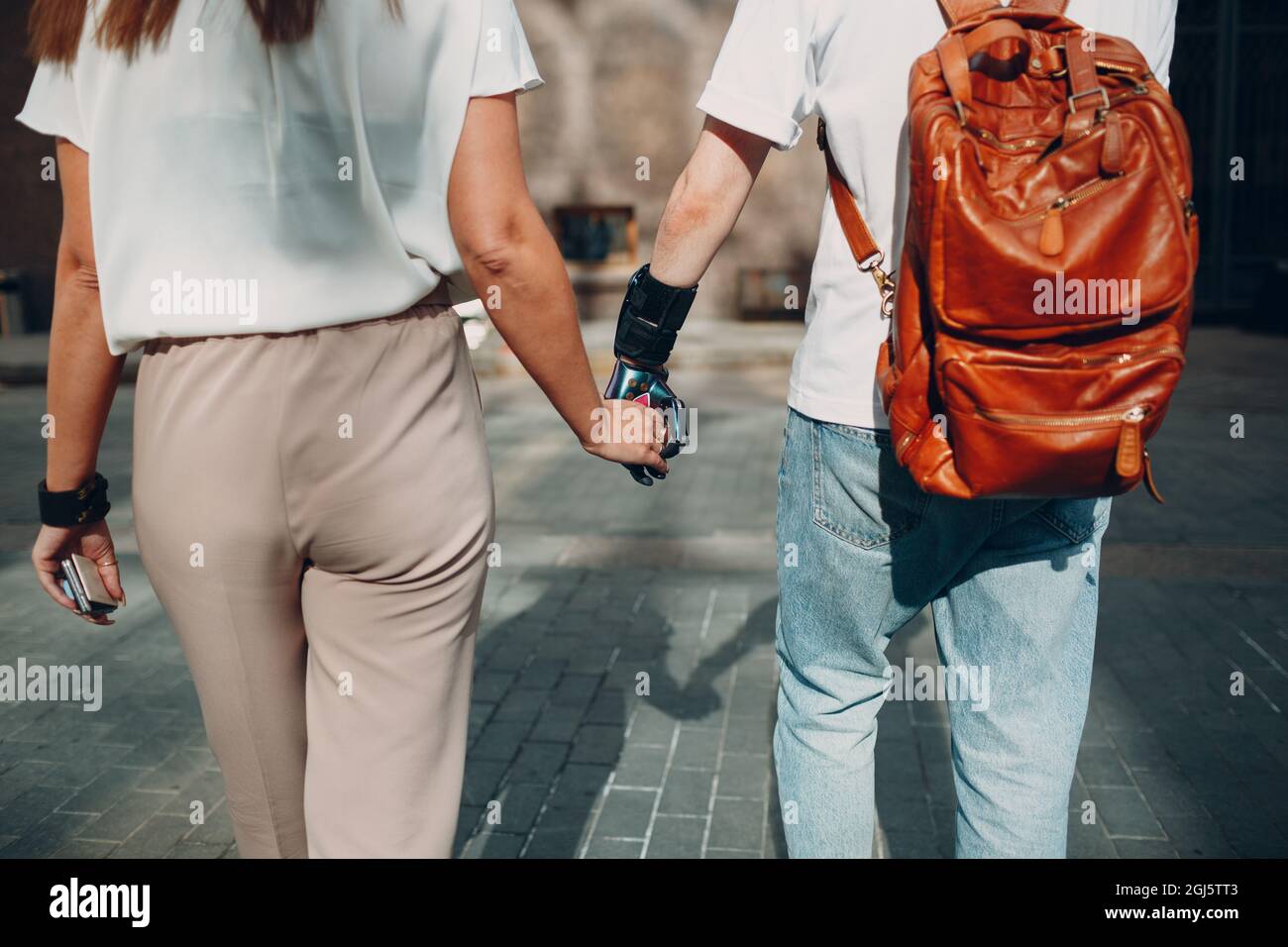 Young disabled man with artificial prosthetic hand walking and holding woman girlfriend hand Stock Photo