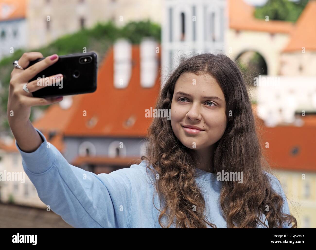 Young girl takes a selfie photo on the background of the historic town, city Czech Krumlov, Czech republic Stock Photo